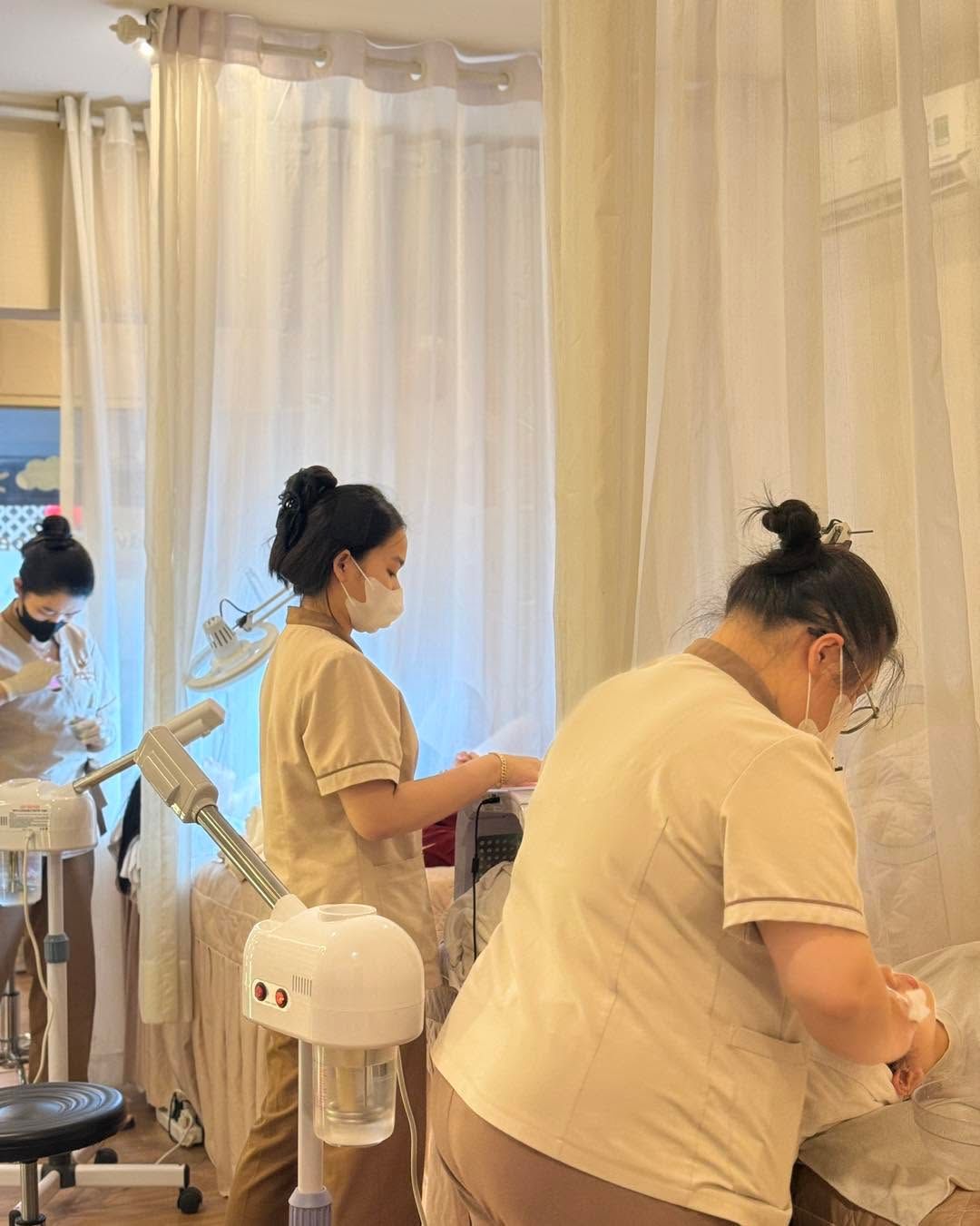 Hai kỹ thuật viên đeo khẩu trang làm việc bên giường, máy xông hơi đặt bên cạnh