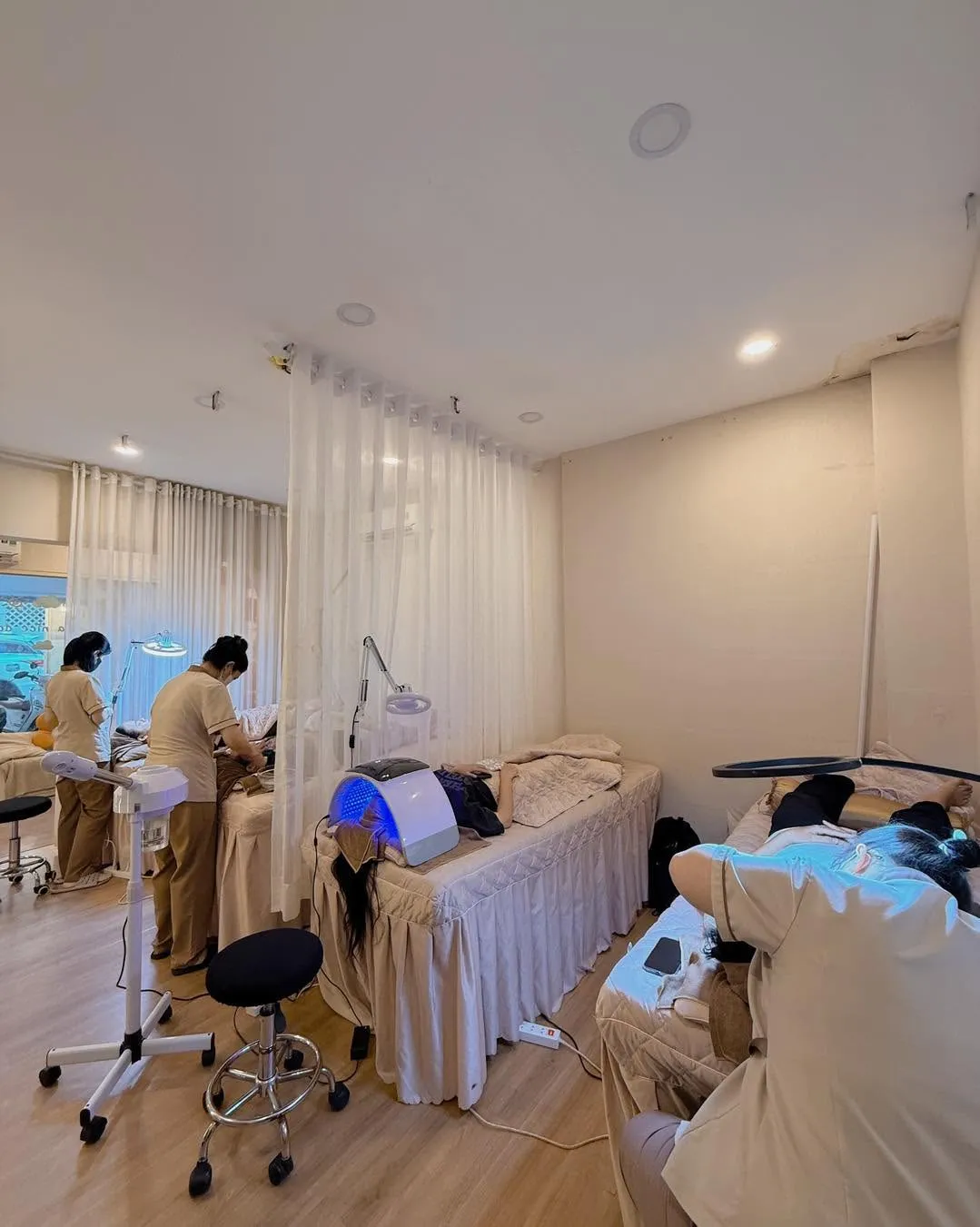 Hai kỹ thuật viên áo be làm dịch vụ cho khách trong phòng có máy đèn LED
