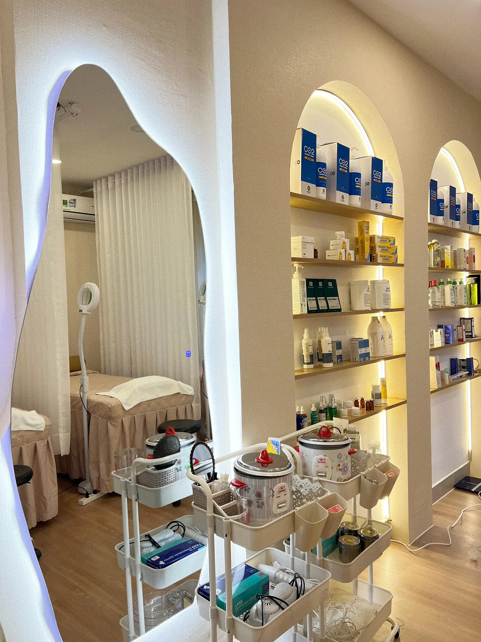 Kệ dược mỹ phẩm và giường facial sau vòm cửa tại Nhung Hong Le Spa